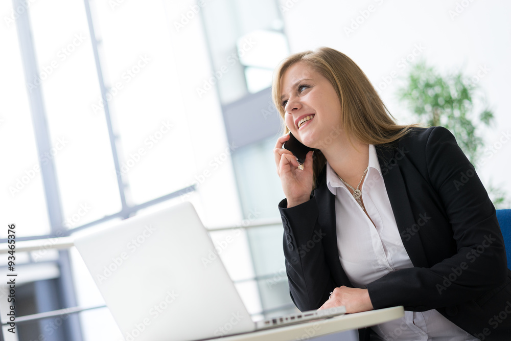 Businesswoman working & sitting at her desk in an office Businesswoman working & sitting at her desk in an office