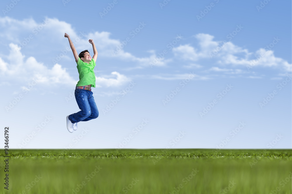 Young boy is jumping in nature on green grass