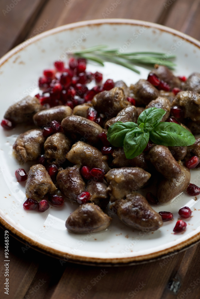 Roasted chicken hearts with pomegranate seeds, close-up Roasted chicken hearts with pomegranate seeds, close-up