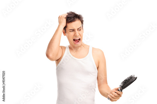 Angry man loosing hair and holding a hairbrush