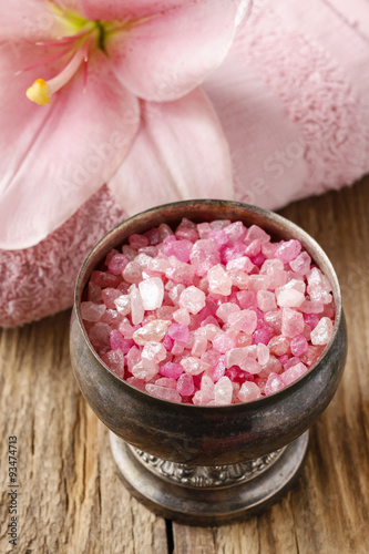 Bowl of pink sea salt and lily flower in the background