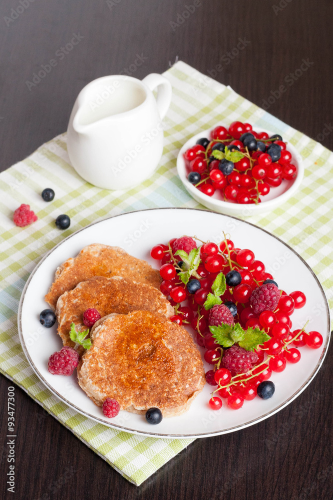 sweet cheese pancakes with fresh berries and milk on black woode