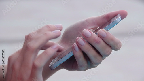 Close-up of woman's hands with nice manicure texting, messaging on smart phone