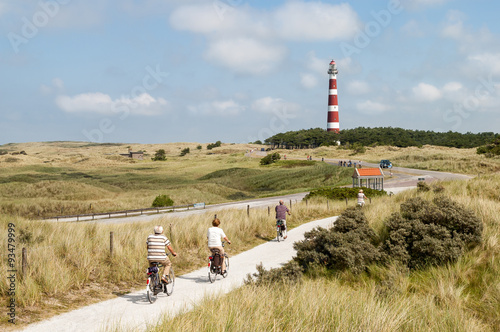 Seniors riding on bicycles in the dunes of Ameland near the lighthouse, Netherlands photo
