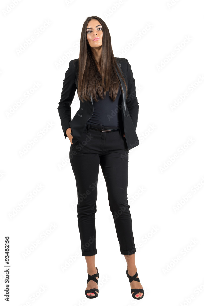 Serious young businesswoman with hands in pockets looking at camera isolated Serious young businesswoman with hands in pockets looking at camera isolated