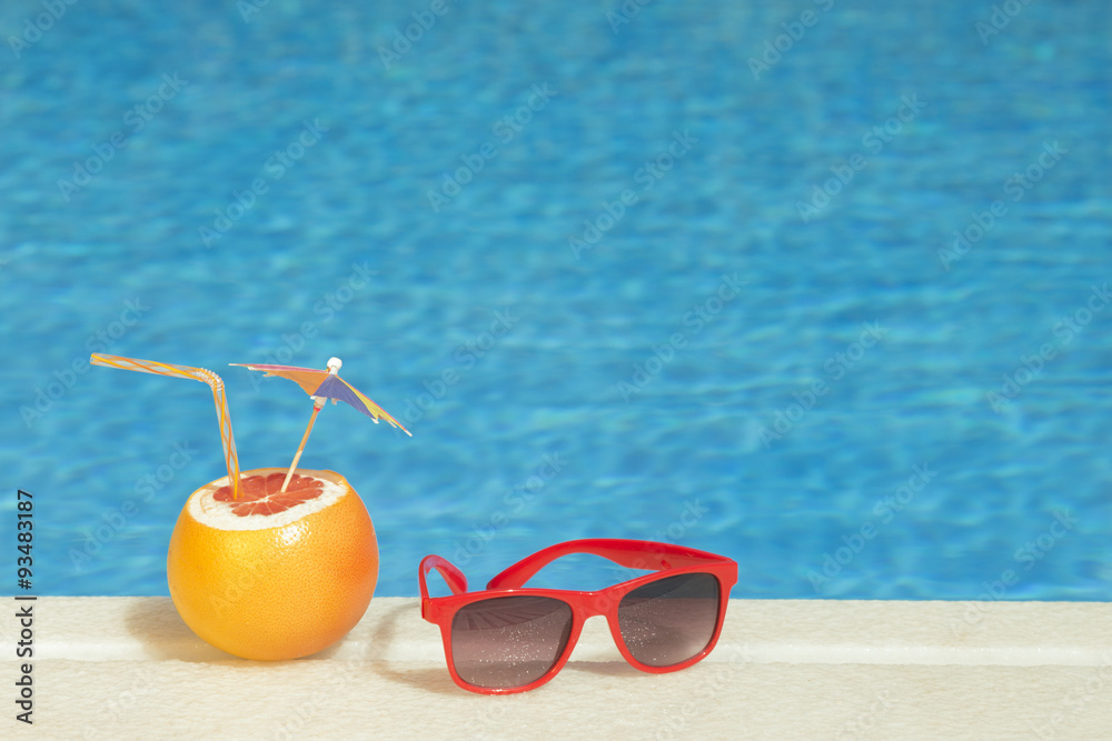Red sunglasses and Grapefruit with drinking straw and paper parasol