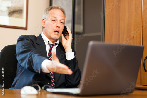 Senior businessman with a phone and a laptop computer