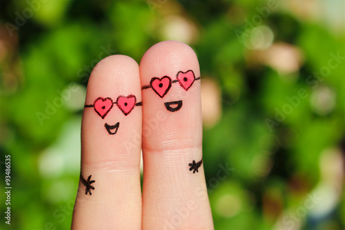 Finger art of a Happy couple. A man and a woman hug in pink glasses in shape of hearts. The concept of love at first sight.