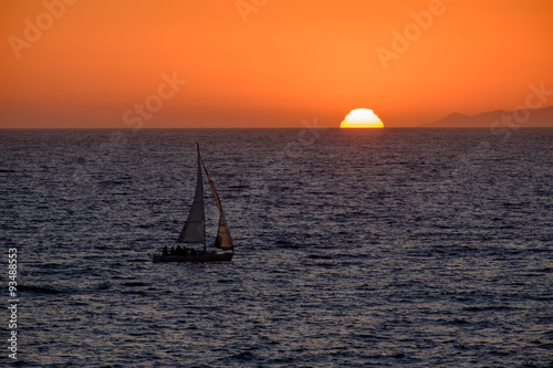 Sailboat nears the sun setting in Redondo Beach, California photo