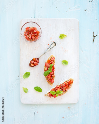 Tomato and basil bruschetta sandwich on white wooden serving