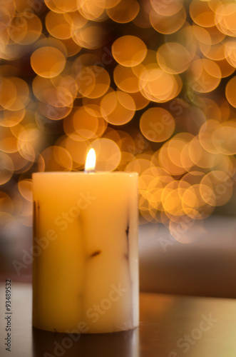 Vela encendida con luces de Navidad desenfocadas de fondo