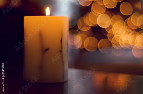 Vela con luces del árbol de Navidad desenfocadas de fondo.