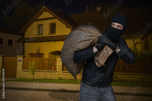 Masked robber or burglar robbed house at night and runs away with full stolen bag