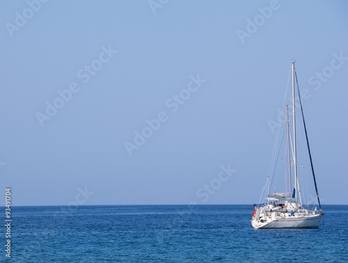 White yacht with sails up on blue sea and sky horizon