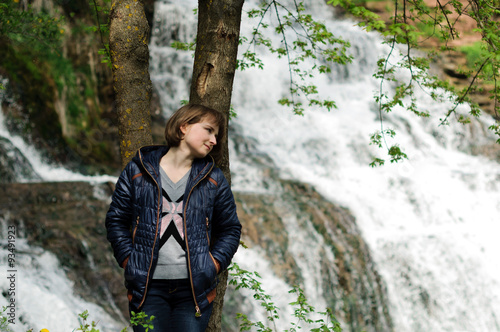 Young girl standing near forest waterfall. Dreaming