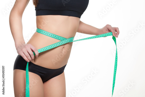 Woman measuring her waistline with a green measuring tape, isolated in white. Perfect Slim Body. Diet
