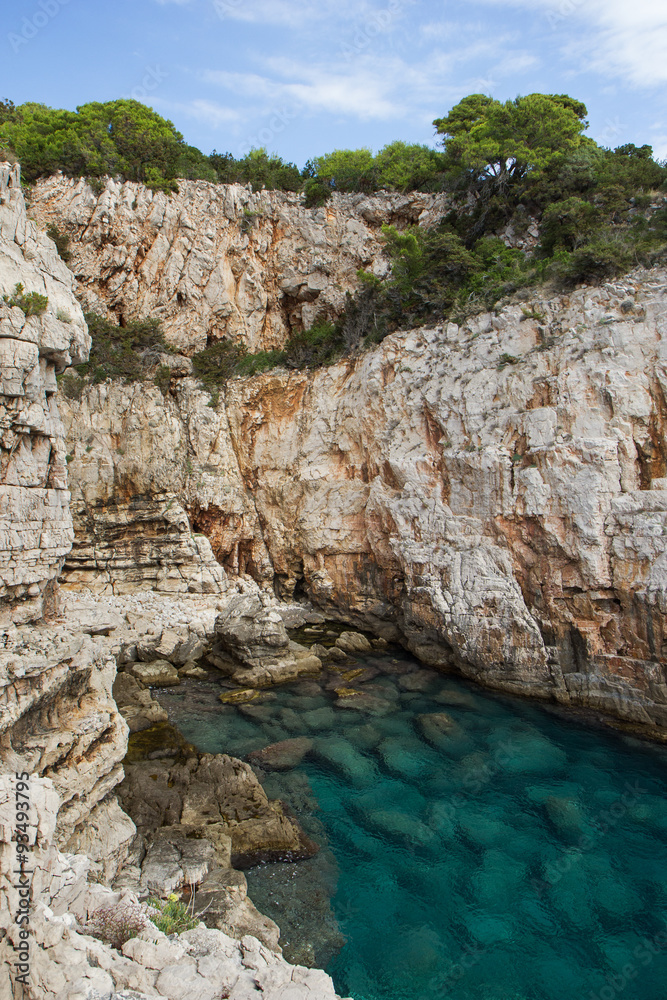 Empty sea cove, shallow water and steep and rugged cliff at the Lokrum Island in Croatia.