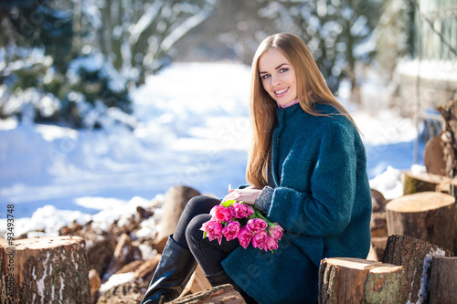 Young woman with a bouquet of tulips at the park. Snow in early spring