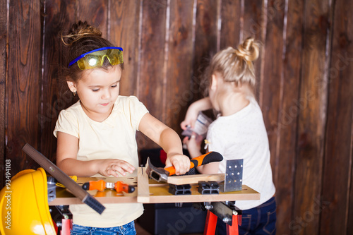 Two little girls making very interesting creations with tools and wood at home