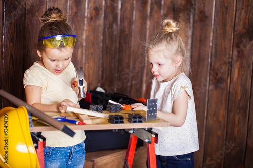 Two little girls making very interesting creations with tools and wood at home