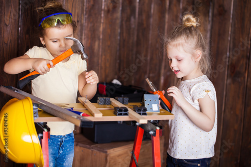 Two little girls making very interesting creations with tools and wood at home