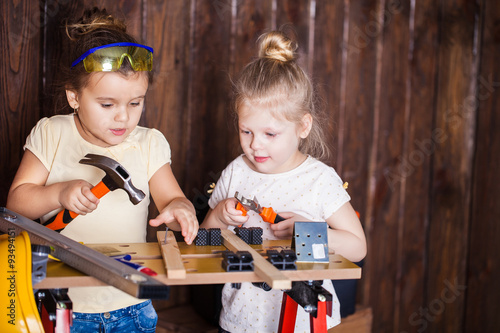 Two little girls making very interesting creations with tools and wood at home