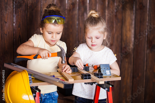 Two little girls making very interesting creations with tools and wood at home