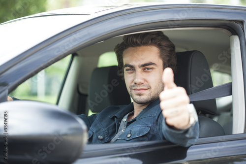 Young man thumbs up gesture in car