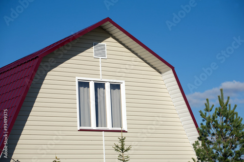 New country house with beige siding and and white plastic window on sunny day closeup