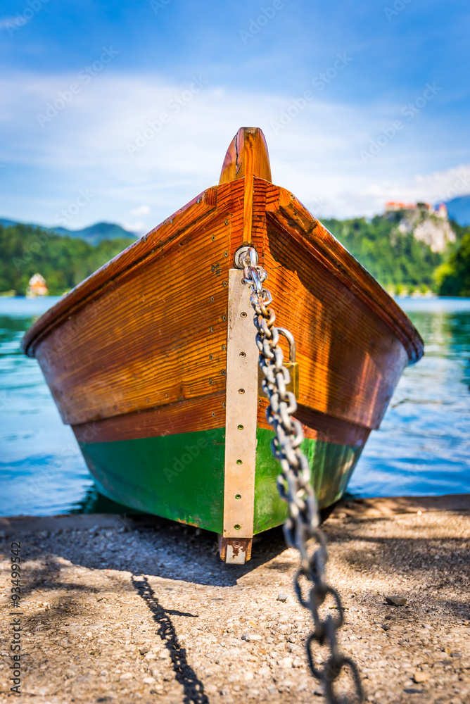 Detail of Anchored Wooden Tourist Boat on Shore of Bled Lake, Slovenia with Bled Castle in Background Detail of Anchored Wooden Tourist Boat on Shore of Bled Lake, Slovenia with Bled Castle in Background