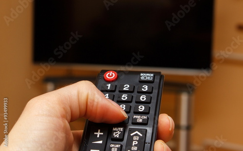 Hand holding remote control for television, choosing channel in TV