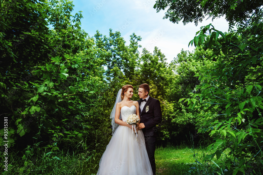 Beautiful wedding couple is standing outdoors at summer park