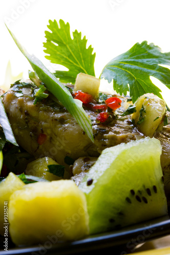 Close up Schweinemedaillon auf Ananas-Kiwi-Salat mit Petersilie, Frühingszwiebeln photo