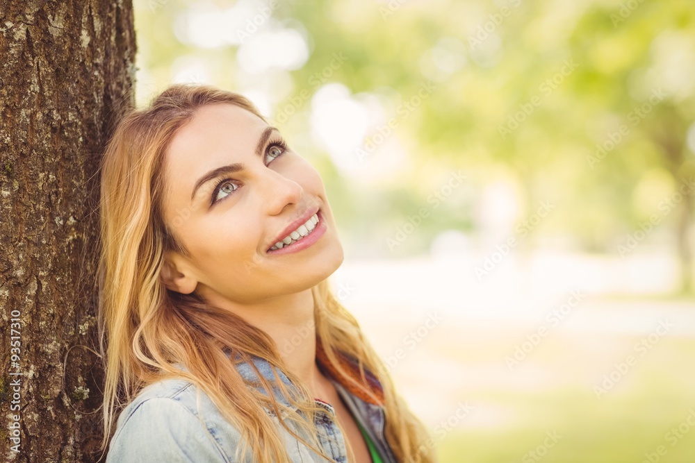 Smiling woman looking up while sitting under tree Smiling woman looking up while sitting under tree
