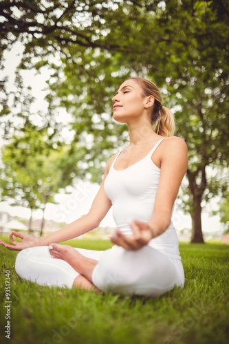 Woman meditating with eyes closed while sitting in lotus pose 