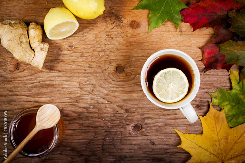 Fototapeta Naklejka Na Ścianę i Meble -  tea with honey and ginger on a wooden table with autumn leaves