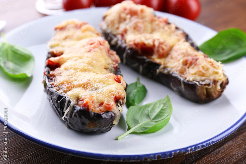 Dish of eggplant with cherry tomatoes and cheese in white plate on wooden table, closeup Dish of eggplant with cherry tomatoes and cheese in white plate on wooden table, closeup