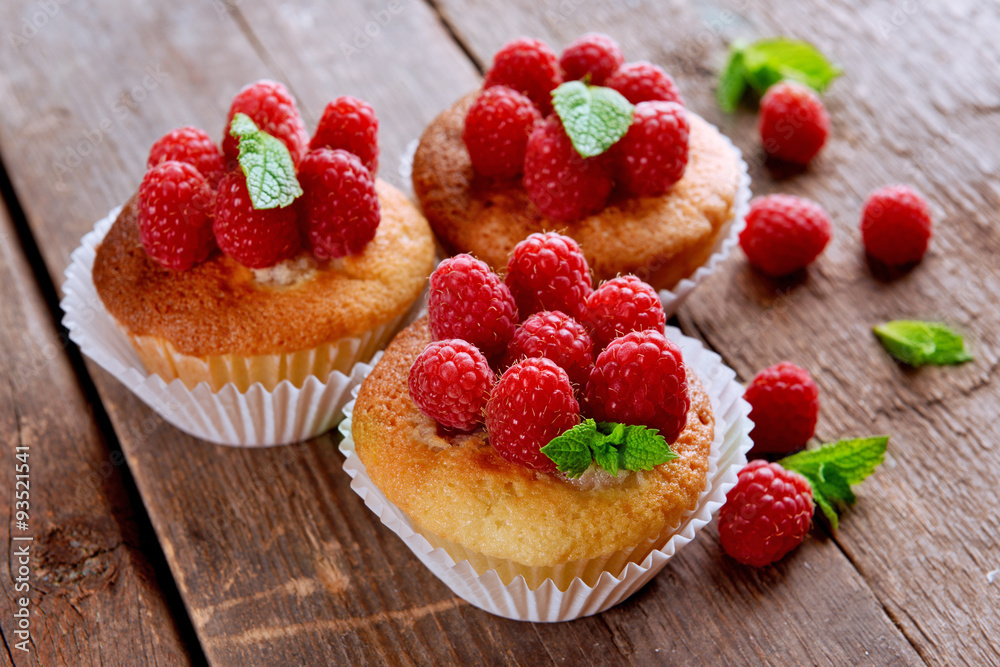 Delicious cupcakes with berries and fresh mint on wooden table close up Delicious cupcakes with berries and fresh mint on wooden table close up