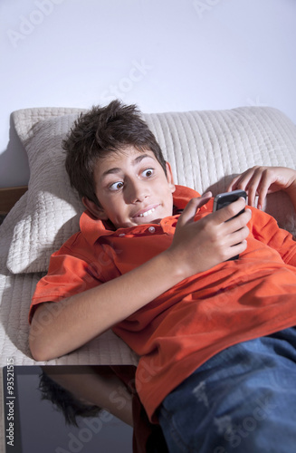 Surprised young boy is playing with smart phone