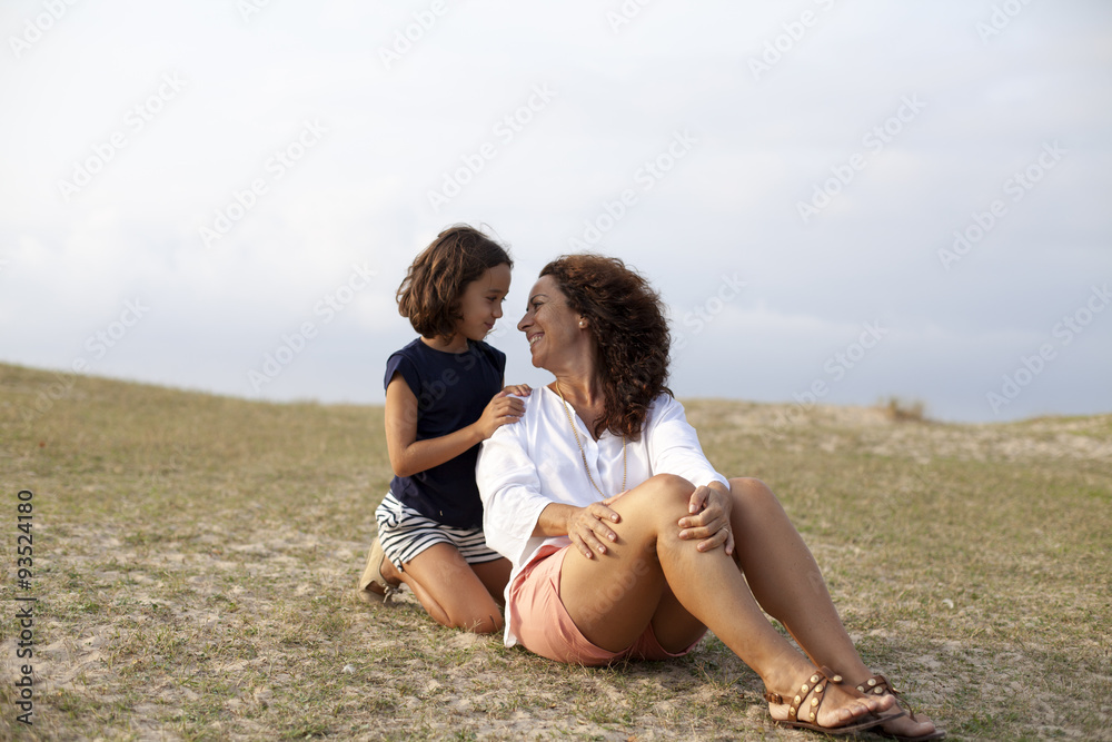 Madre sonriendo con su hija sobre la hierba