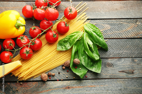 Pasta spaghetti with tomatoes, cheese and basil on rustic wooden background