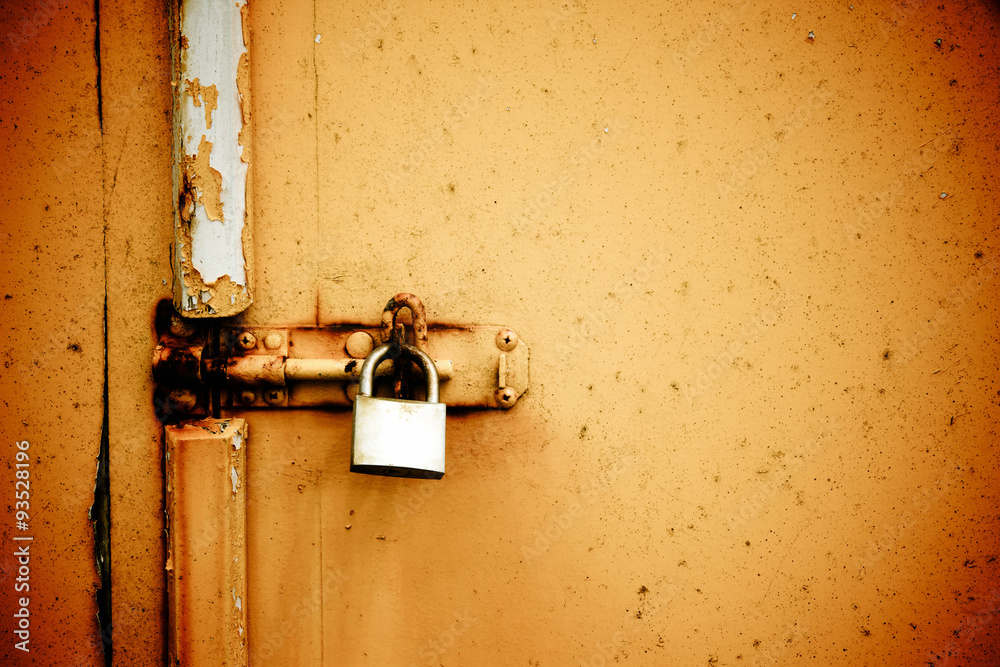 Rusty padlock on old orange painted wooden door Rusty padlock on old orange painted wooden door