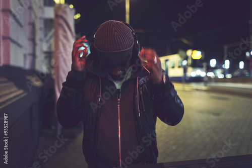 Photography Urban afro man with woolen cap and headphones in city at night w
