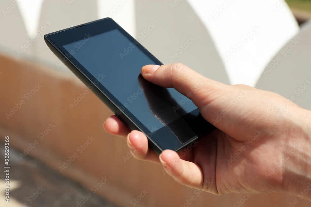 Female hand holding smart mobile phone outdoors Female hand holding smart mobile phone outdoors