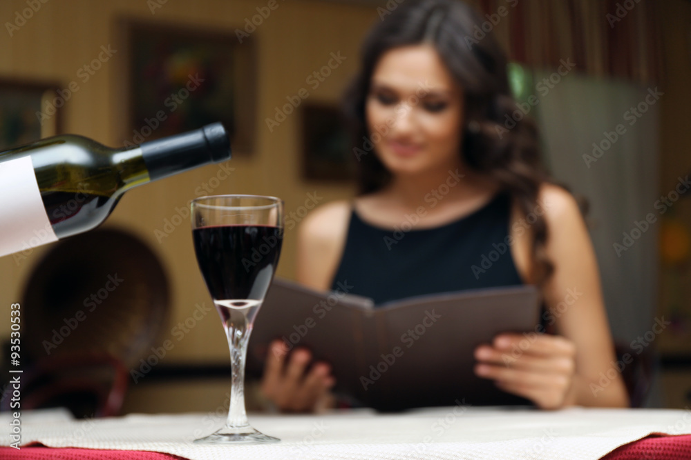Young pretty lady at the restaurant. Waiter pouring wine in a glass Young pretty lady at the restaurant. Waiter pouring wine in a glass