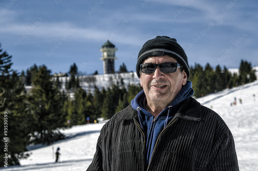 Portrait of elderly man in sunglasses against the backdrop of a tourist ski resort.