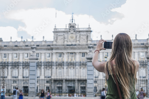 Young tourist taking photos of the Royal Palace in Madrid.