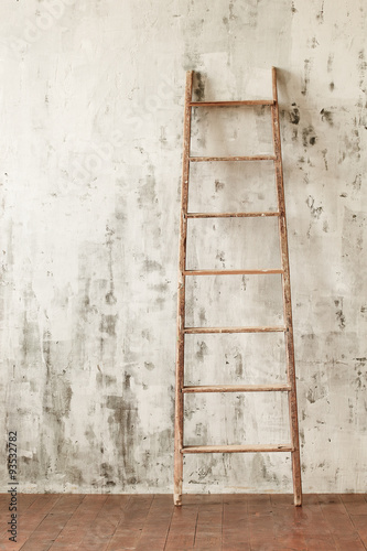 A wooden staircase in an empty room on the background of a concrete wall