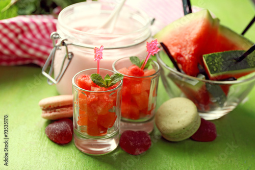Watermelon ice cream in glass jars on color wooden background