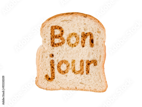 Word bonjour (meaning good morning in French) written on a toasted slice of bread